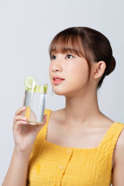 Salatalık dilimli bir bardak su tutan hoş bir kadın.