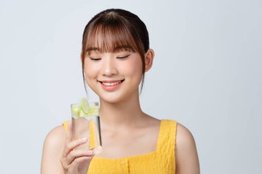 Salatalık dilimli bir bardak su tutan hoş bir kadın.