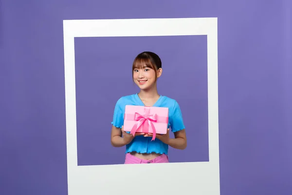 Photo of lovely asian millennial lady  hold gift box isolated on color background