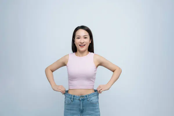 Erfolgreiche Gewichtsabnahme Asiatische Frau Mit Großen Jeans Nach Effektiver Ernährung lizenzfreie Stockfotos