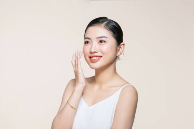 Neşeli bayan yanak tenine dokunuyor estetik ideal cildin tadını çıkarıyor bej rengi üzerine izole edilmiş