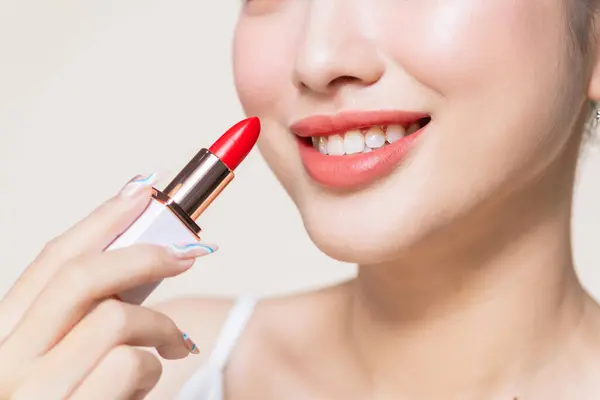 Wanita Muda Mengoleskan Lipstik Pada Beige Stok Gambar