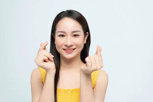 美丽的年轻亚洲女人在孤独的白色背景上表现出微小的心指 免版税图库图片
