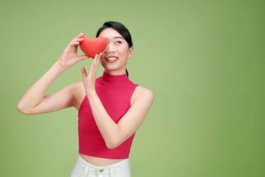 Kırmızı Kalbini Yeşil Arkaplanda Tutan Kadın Gülümsüyor