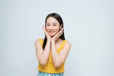 Genç ve güzel siyah uzun saçlı kadın beyaz arka planda kendine güvenen bir poz veriyor..