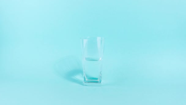 4Kガラスは半分空またはフル 透明なガラスは水で満たされている 楽観的で悲観的な人生観の概念 青の背景 動くなよ コピースペース — ストック動画