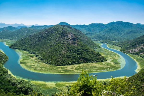 Pavlova Strana Manzarası. Yeşil dağların güzel yaz manzarası, mavi gökyüzü ve Skadar Gölü 'ne akan Crnojevica nehrinin kıvrımları. Karadağ. Seyahat kavramı.