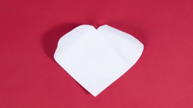 4k Big white heart appears on red background. Symbol of love. Greeting card. Concept of valentine's holiday, wedding and other occasions to express love. Stop motion animation. Flat lay.
