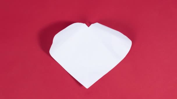 4K大白心出现在红色背景上 爱情的象征 问候卡 情人节 婚礼等场合表达爱意的概念 停止动作动画 平躺在床上 — 图库视频影像