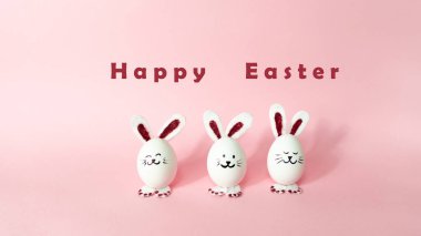 Mutlu Paskalyalar. Açık pembe renkli arka planda izole edilmiş beyaz tavuk yumurtasından yapılmış üç sevimli tavşan. Tatil tebrik kartı. Boşluğu kopyala.