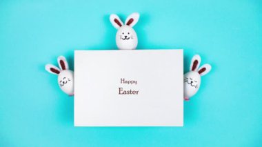 4k Three Easter bunnies made of white chicken eggs emerge from behind a sheet of white paper. Holiday greeting card 