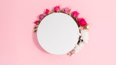 White circle background is decorated natural flowers buds. Pink background. Template for text or design. Valentine's, mother's day holiday, wedding and and other occasions.