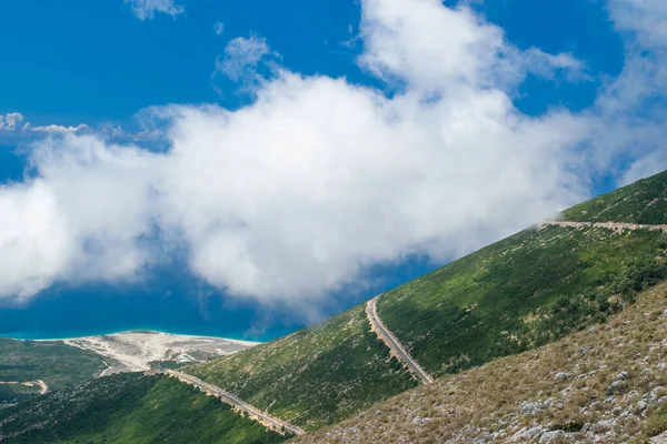 White fog high in the mountains on the Llogara pass. View from the highlands on serpentine road to the pass.Landscape of Albanian Riviera, Palasa beach and white clouds against a blue sky. Albania.