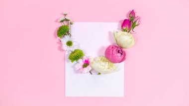Natural red and white flowers buds in open envelope near blank sheet. Valentine's, mother's day holiday, wedding and other occasions. Pink background. Copy space.