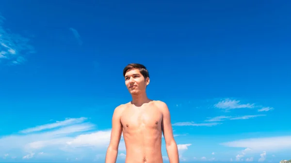 하늘을 배경으로 해변에서 햇볕에 그을린 남자의 방학이라는 바다를 건너서 목욕을 — 스톡 사진