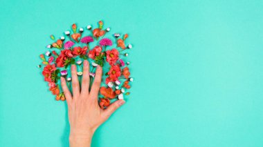 Kadın palmiyesinin yanında doğal kırmızı ve beyaz çiçekler. Aşk ve güzellik kavramı. Turkuaz arka plan. Uzayı kopyala Düz yatıyordu. Tebrik kartı.