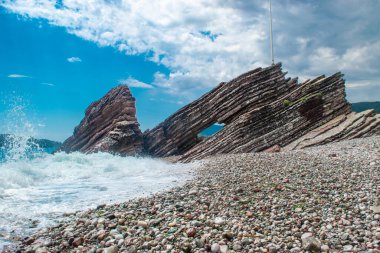Halka açık kumsalda güzel kayalar. Rafailovici Esort kasabaları. Dağlı. Adriyatik Denizi. Yaz güneşli bir gün. Deniz kenarı tatil kavramı. 