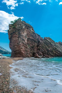 Halka açık kumsalda güzel kayalar. Rafailovici Esort kasabaları. Dağlı. Adriyatik Denizi. Yaz güneşli bir gün. Deniz kenarı tatil kavramı. 