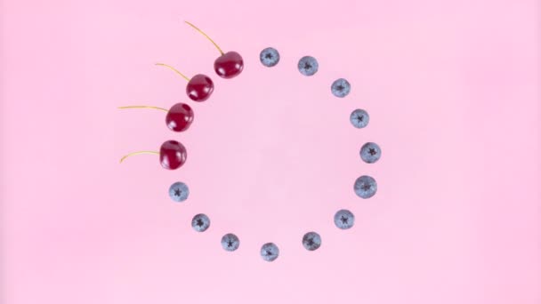 4K成熟的樱桃交替排列成圆形 变成蓝莓 粉色背景 浆果季节的概念和适当的营养 粉色背景 复制空间 平躺在床上停止动作动画 — 图库视频影像