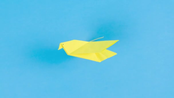 Papel Amarillo Origami Paloma Vuela Agitando Sus Alas Fondo Azul — Vídeos de Stock