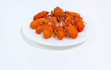 Group of boiled river red crayfish are laid out on a plate. White background. Catching crayfish for human consumption. Delicious food.