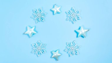 Kar taneleri ve yıldızların Noel süslemeleri bir çember oluşturur. Mavi arka plan. Kutlama çerçevesi ya da kartpostal. Boşluğu kopyala.