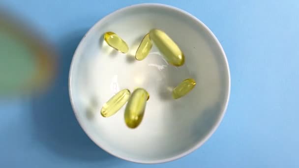Yellow Transparent Capsules Liquid Omega Fall White Bowl Slow Motion — ストック動画