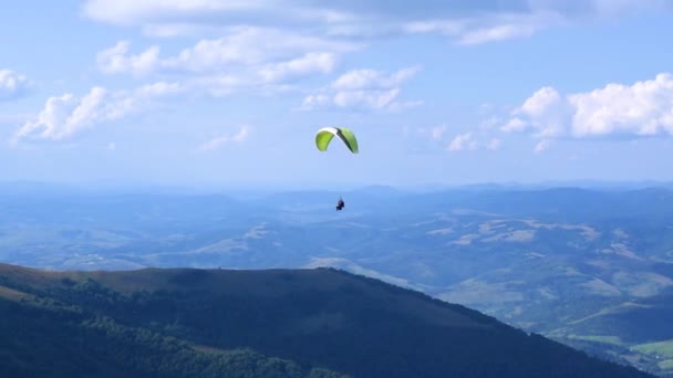 パラグライダーのインストラクターと乗客がタンデムでパラグライダーを飛んでいる 美しい夏の晴れた日 高い山カルパティア風景 青い曇った空 — ストック動画
