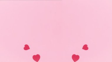 4k On pink background, group of red paper hearts, symbols of love, flies by. Greeting card. Valentine's day holiday. Template for text or design. Copy space. Flat lay. Stop motion animation.