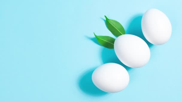 Três Ovos Galinha Branca Fundo Azul Folhas Verdes Naturais Movem — Vídeo de Stock