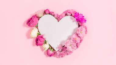 Beyaz kağıt kalbin yanında doğal güller ve sakura çiçekleri. Anneler, kadınlar, doğum günü ya da başka bir gün için tebrik kartı. Uzayı kopyala Metin için şablon. Düz Yat.