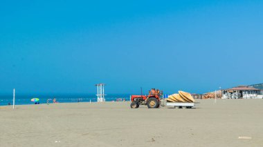 Ulcinj, Karadağ - 09 Temmuz 2021: İşçiler Long Beach 'i (Velika plazası) bir traktörle donatıyorlar. Güneşli mavi deniz manzarası. Adriyatik Denizi.