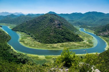 Pavlova Strana Manzarası. Yeşil dağların güzel yaz manzarası, mavi gökyüzü ve Skadar Gölü 'ne akan Crnojevica nehrinin kıvrımları. Karadağ. Seyahat kavramı.