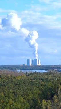 Lippendorf Enerji İstasyonu 'nun Leipzig yakınlarındaki soğutma kulelerinden yükselen dumanın manzarası. Saksonya. Almanya. Enerji santralinin silueti mavi gökyüzüne ve yeşil ormana hakim..