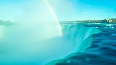 Niagara At Nalı Şelalesi 'nin bulanık akıntılarına yakın çekim. Parlak gökkuşağı su bulutuna düşer. Kanadalı tarafından bak. Mavi gökyüzü günü.