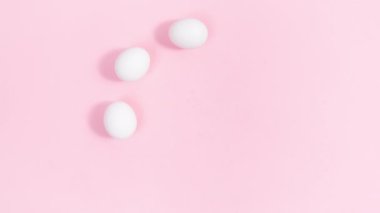 Daire şeklinde dizilmiş beyaz yumurtalar doğal çiçek tomurcuklarıyla süslenir. Pembe arka plan. Paskalya tatili. Tebrik kartı. Tasarım veya metin şablonu. Hareketi durdur.