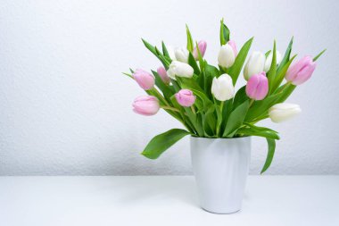 Beyaz vazoda taze beyaz ve mor laleler. Tebrik kartı. Aşk kavramı, kadınlık, zarafet ya da ilkbaharın gelişi, ayrıca romantik çay partisi. Boşluğu kopyala.