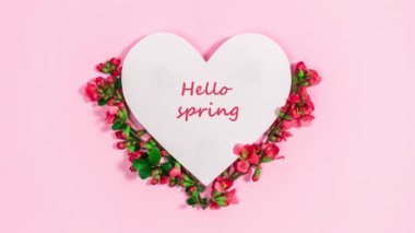 Merhaba bahar. Tebrik kartı. Beyaz kağıt kalbin yanında bahar kırmızı tomurcukları ve çiçekleri olan doğal dallar. Baharın gelişi kavramı.