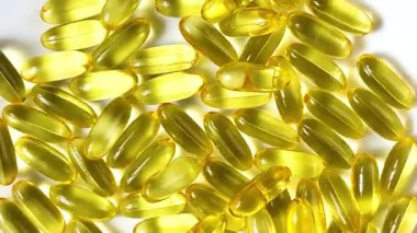 Yellow transparent capsules with liquid Omega 3 on a white background. The concept of maintaining and improving health, Fish oil is an essential supplement for wellness. Slow motion. Close up.