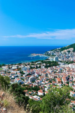 Budva tatil köyünün panoramik manzarası mavi gökyüzü arka planında. Üst Manzara. Adriyatik kıyısındaki eski ve yeni şehrin mimarisi. Karadağ. Yaz güneşli bir gün.