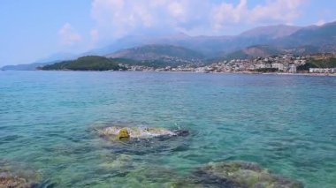 Himare 'nin dağların eteğindeki çakıl taşlı sahil kasabasının güzel yaz bulutları manzarası. Adriyatik denizleri. Arnavutluk. Yaz tatili ve rahatlama kavramı.