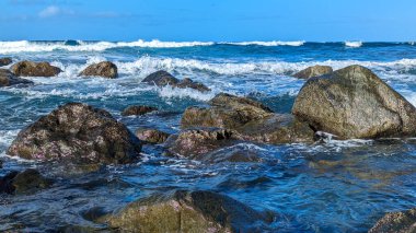 Kanarya Adaları 'ndaki Benijo sahilinde dalgalarda sörf yapan büyük güzel taşlar. Atlantik Okyanusu. Bulutlu mavi güneşli gökyüzü. Benijo plajı, Anaga Kırsal Parkı, Santa Cruz de Tenerife belediyesi. İspanya.
