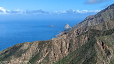 Yeşil dağlar ve uçurumlardan oluşan güzel bir manzara. Mirador Bailadero 'nun sahile ve Atlantik Okyanusu' na bakış açısı. Bulutlu mavi güneşli gökyüzü. Anaga Kırsal Parkı, Tenerife. Kanarya Adaları, İspanya.