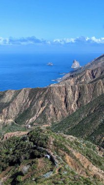 Yeşil dağlar ve uçurumlardan oluşan güzel bir manzara. Mirador Bailadero 'nun sahile ve Atlantik Okyanusu' na bakış açısı. Bulutlu mavi güneşli gökyüzü. Anaga Kırsal Parkı, Tenerife. Kanarya Adaları, İspanya.