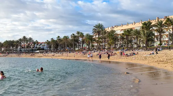 Playa de las Americas, Tenerife, İspanya - 7 Ocak 2025: İnsanlar geniş, güzel kumlu plajda güneşlenip yüzüyor ve tatillerini Atlantik kıyısında geçiriyorlar..