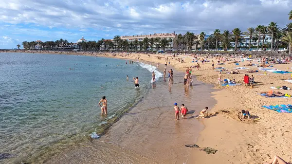 Playa de las Americas, Tenerife, İspanya - 7 Ocak 2025: İnsanlar geniş, güzel kumlu plajda güneşlenip yüzüyor ve tatillerini Atlantik kıyısında geçiriyorlar..