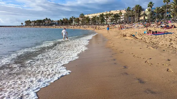 Playa de las Americas, Tenerife, İspanya - 7 Ocak 2025: İnsanlar geniş, güzel kumlu plajda güneşlenip yüzüyor ve tatillerini Atlantik kıyısında geçiriyorlar..