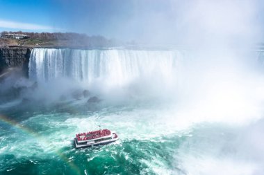 At nalı şelalesinin güzel manzarası, Niagara Şelalesinin en büyük üç şelalesi. Turistli gemi şelale ve yükselen su bulutlarına doğru yelken açıyor. Ön planda gökkuşağı. Kanada tarafından görünüyor..