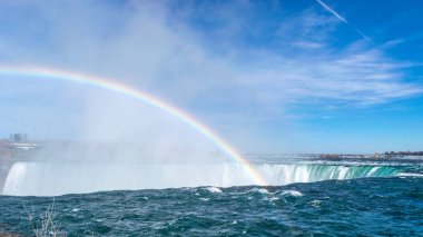 Niyagara Şelalesi, Ontario 'daki Table Rock Center' dan izlenen Horseshoe Falls. Parlak gökkuşağı su bulutuna düşer. Kanadalı tarafından bak. Mavi gökyüzü günü.