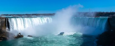 At nalı şelalesinin güzel manzarası, Niagara Şelalesinin en büyük üç şelalesi. Turistli tekne şelale jetlerine ve yükselen su bulutuna yakın. Kanadalı tarafından bak. Güneşli bir gün.